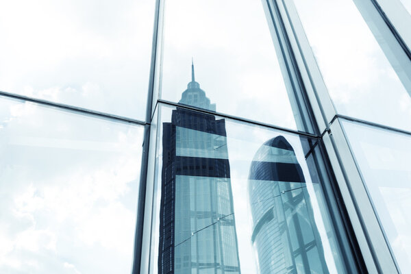 A skyscraper with glass walls and the reflection of landmarks on the opposite side