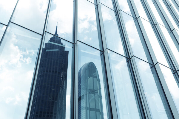 A skyscraper with glass walls and the reflection of landmarks on the opposite side