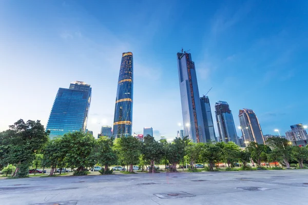 Skyscrapers of a modern city at dusk with street lamps — Stock Photo, Image