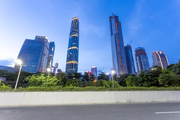 Skyscrapers of a modern city at dusk with street lamps — Stock Photo, Image