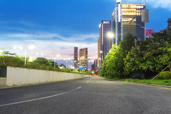 небоскребы современного города в сумерках с уличными фонарями
