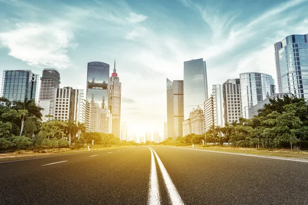 Asphalt road and skyscrapers under sunbeam — Stock Photo, Image