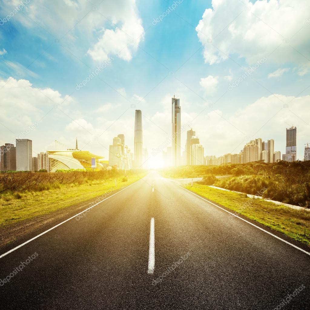 asphalt road and skyscrapers under sunbeam