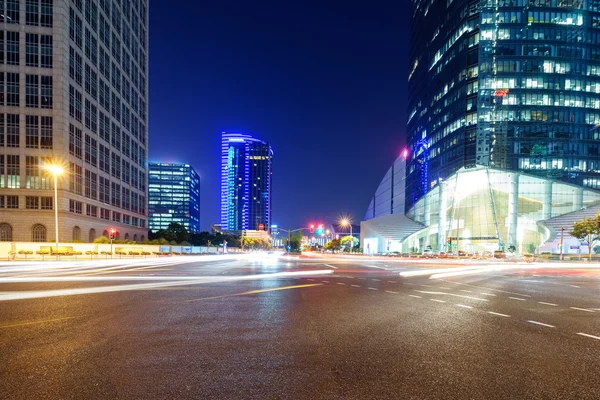 Asfaltová silnice poblíž mrakodrapy v noci — Stock fotografie