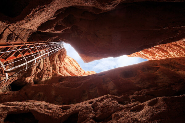 top of cave with iron ladder in red sandstone