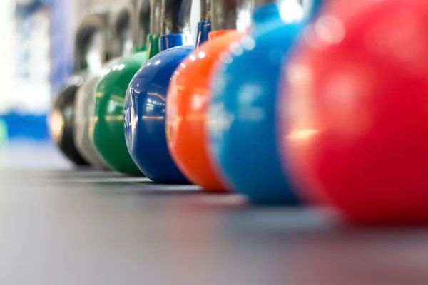 Colorful kettlebells lining on table — Stock Photo, Image