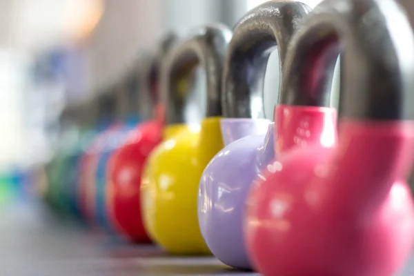 Colorful kettlebells lining on table — Stock Photo, Image