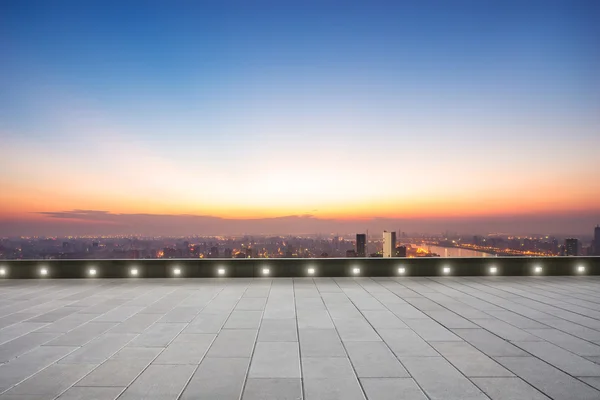 empty floor in front of cityscape at sunrise