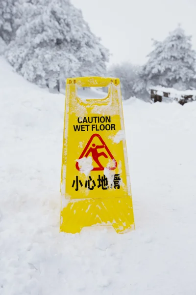 Warning caution sign board on snow floor — Stock Photo, Image