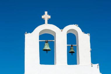 Santorini'de mavi bir gökyüzü üzerinde beyaz çan kulesi
