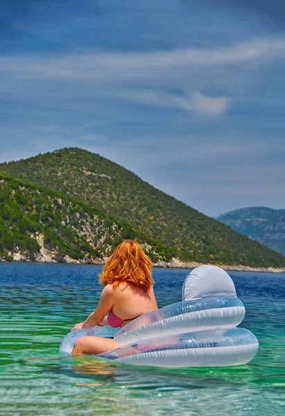 Mulher nova no colchão inflável que relaxa no mar — Fotografia de Stock