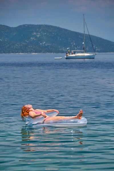 Mujer joven en colchón inflable en el mar — Foto de Stock