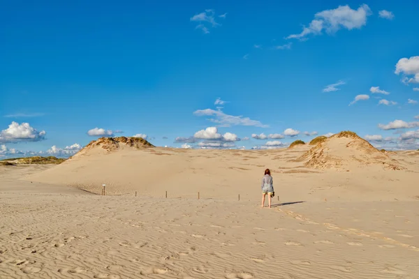 Молодая рыжая женщина гуляет под солнцем по бесконечным песчаным дюнам — стоковое фото