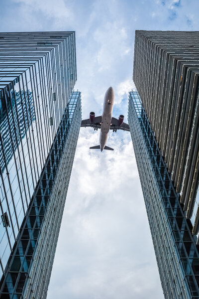 Upward view of the airplane between the two glass skyscrapers