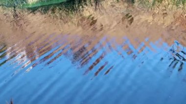 Su deposundaki suyun yüzeyinde küçük dalgalanmalar ve mavi gökyüzünün yansıması.