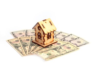 Evin ahşap bir modeli ipotek yatırımının sembolü olarak Amerikan doları yığınının üzerinde duruyor.
