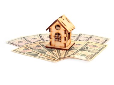 Evin ahşap bir modeli ipotek yatırımının sembolü olarak Amerikan doları yığınının üzerinde duruyor.