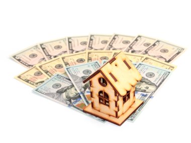 Evin ahşap bir modeli ipotek yatırımının sembolü olarak Amerikan doları yığınının üzerinde duruyor.
