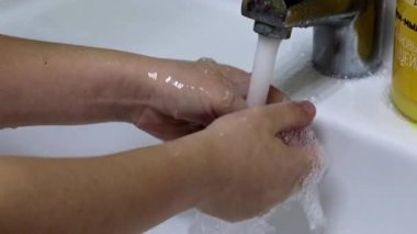 Adam ellerini temiz suyun altında yıkar.