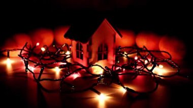 Bir Noel çelenginin parlak ışığı ve refah ve refahın sembolü olarak ahşap bir ev.