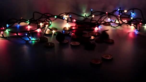 Een Stapel Goudkleurige Munten Een Kerstslinger Licht — Stockvideo