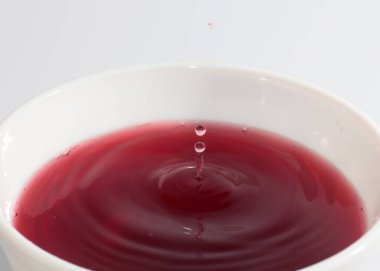 Parlak kırmızı kan damlaları sıvının yüzeyine düşer.