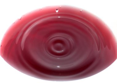 Parlak kırmızı kan damlaları sıvının yüzeyine düşer.