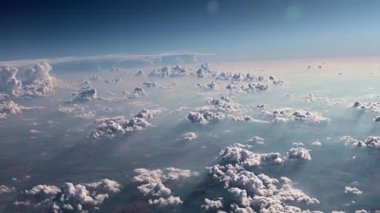 Bir uçak penceresinden dışarı bakarken yerin üstünde kümülüs bulutları