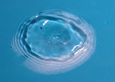 Düşen temiz su damlası ve sıvının yüzeyine çarpan bir şok.