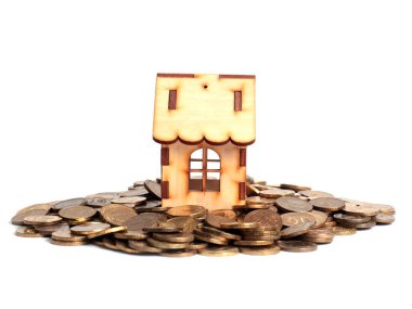 Bir yığın metal para ve ipotek kredisi sembolü olarak ahşap bir ev.