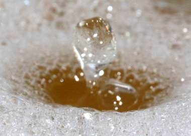 Köpüklü kirli bir sıvının üzerine bir damla temiz su düşer.