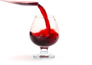 Bardaktaki kırmızı şarabın yüzeyinde ince kıvrımlar var.