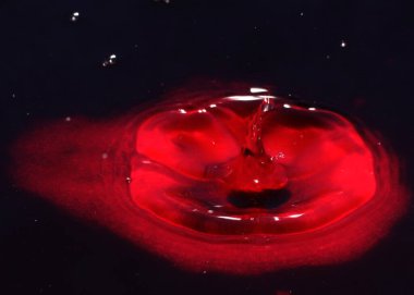 Kirli zehirli suyun yüzeyine kan kırmızı sıvı damlıyor.