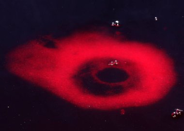 Kirli zehirli suyun yüzeyine kan kırmızı sıvı damlıyor.