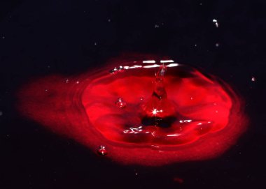 Kirli zehirli suyun yüzeyine kan kırmızı sıvı damlıyor.