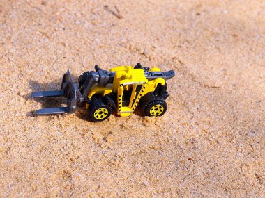 Nehir kumunun geniş bir yüzeyi üzerindeki bir yükleyicinin plastik modeli