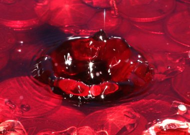 Su yüzeyine bir damla kırmızı sıvı ve bir avuç Rus metal rublesi düşer.