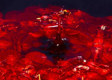 Su yüzeyine bir damla kırmızı sıvı ve bir avuç Rus metal rublesi düşer.