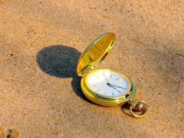 貴金属製のケースの中にあるアンティークの懐中時計は時間の象徴として砂の上にあります — ストック写真