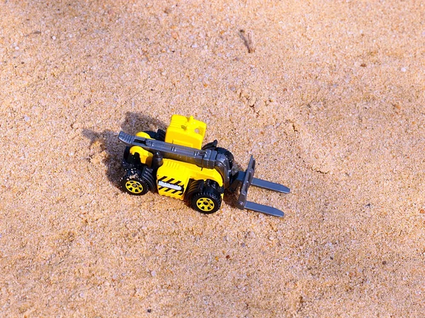 plastic model of a loader on a large surface of river sand