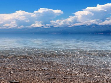 Güneşli bulutlu gökyüzünün altında güzel bir deniz plajı dinlenme ve spor yeri olarak kullanılıyor.