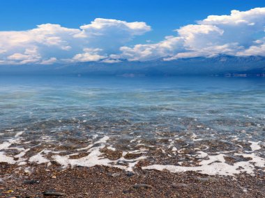 Güneşli bulutlu gökyüzünün altında güzel bir deniz plajı dinlenme ve spor yeri olarak kullanılıyor.
