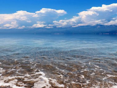 Güneşli bulutlu gökyüzünün altında güzel bir deniz plajı dinlenme ve spor yeri olarak kullanılıyor.