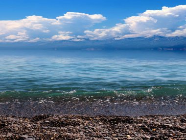 Güneşli bulutlu gökyüzünün altında güzel bir deniz plajı dinlenme ve spor yeri olarak kullanılıyor.