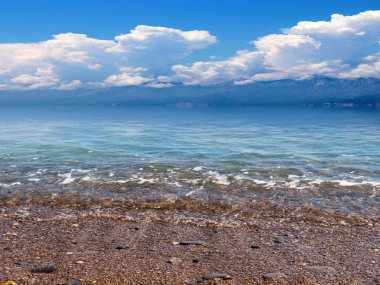 Güneşli bulutlu gökyüzünün altında güzel bir deniz plajı dinlenme ve spor yeri olarak kullanılıyor.