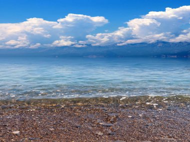 Güneşli bulutlu gökyüzünün altında güzel bir deniz plajı dinlenme ve spor yeri olarak kullanılıyor.