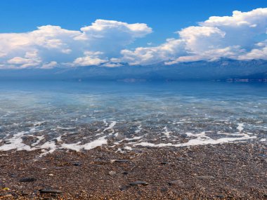 Güneşli bulutlu gökyüzünün altında güzel bir deniz plajı dinlenme ve spor yeri olarak kullanılıyor.