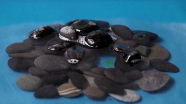 Sıvının yüzeyindeki temiz su damlası taşların arasında.