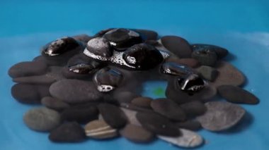 Sıvının yüzeyindeki temiz su damlası taşların arasında.