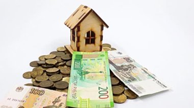 Rus rublesinden dökülen kağıt paralar ve bozuk paraların üzerinde ahşap bir ev.